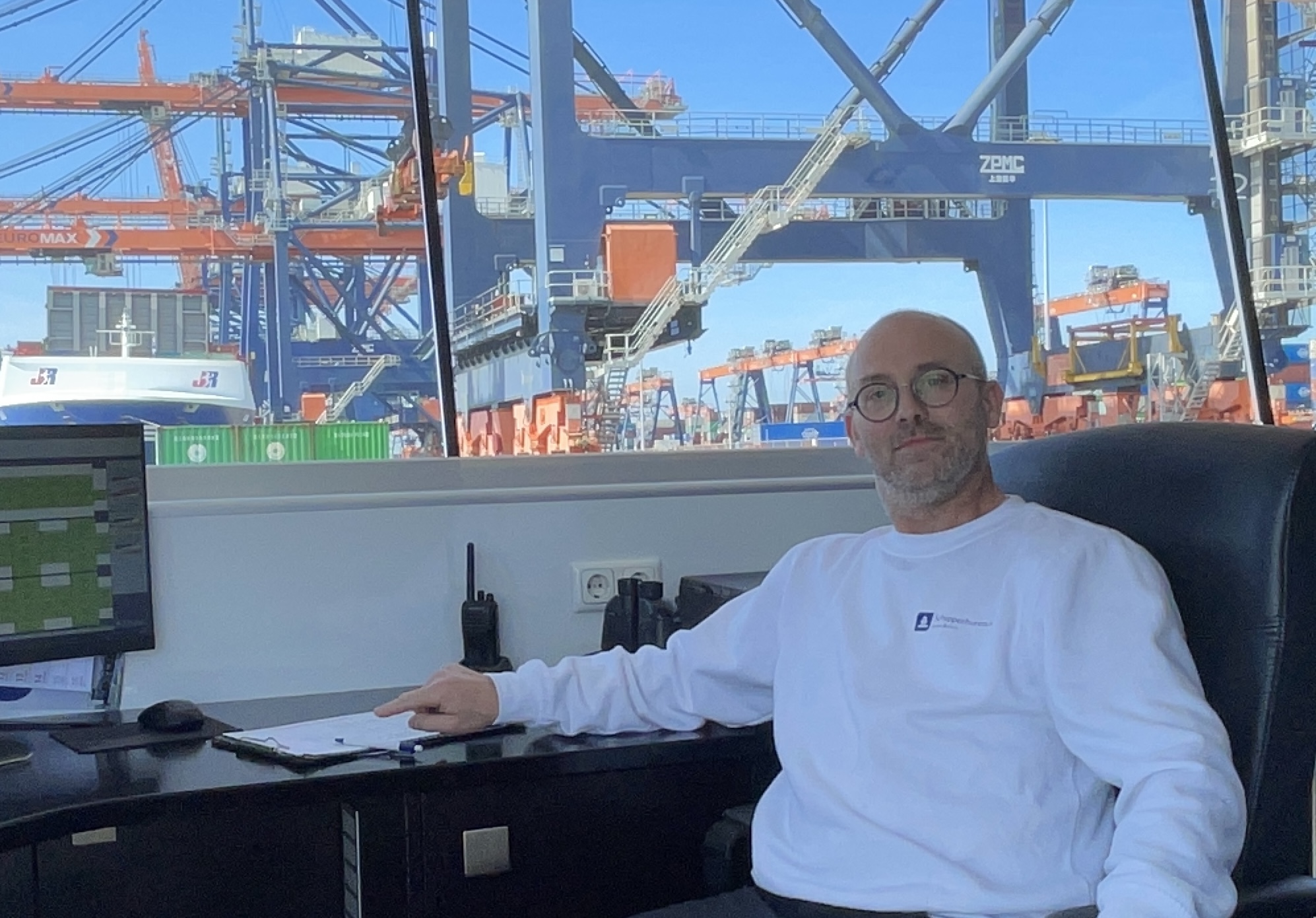 Ramon Beerens in de stuurhut van een binnenvaartschip met containerterminal op de achtergrond
